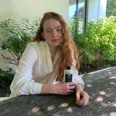 a woman sitting at a picnic table with a bottle of sunscreen in front of her