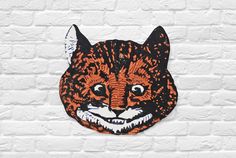 an orange and black cat face on a white brick wall