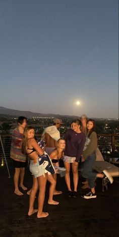 a group of people standing on top of a roof next to each other at night