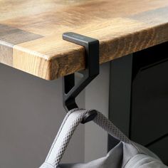 a close up of a metal handle on a microwave oven door with a wooden counter top in the background