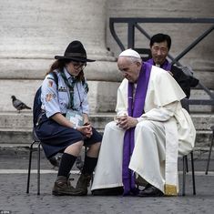 two men sitting on chairs next to each other in front of a large white building