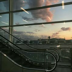 an escalator in front of a window at sunset