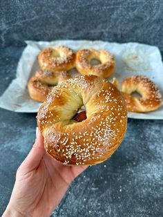 a hand holding a bagel with sesame seeds