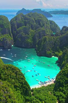 an aerial view of boats in the water surrounded by mountains