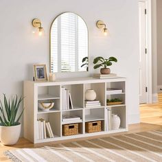 a living room with a white book shelf and mirror