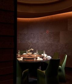 a round table with green chairs in a dimly lit dining room, set for four