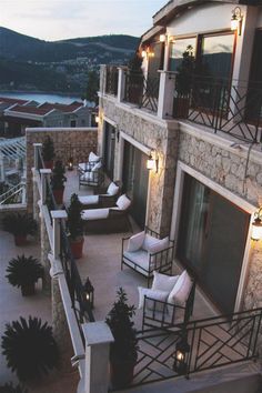 an outdoor patio with chairs and lights on the balcony overlooking a body of water at dusk