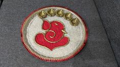 a close up of a red and white brooch on a gray jacket with gold accents