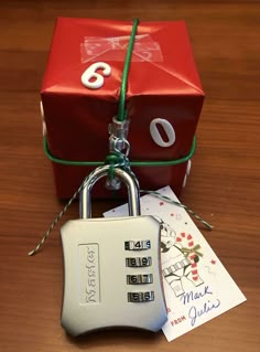 a red box with a padlock attached to it sitting on top of a wooden table