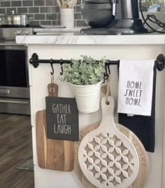 kitchen utensils hanging on the wall next to a potted plant and cutting board