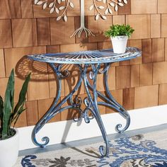 a blue table sitting in front of a wall with a plant on top of it