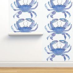 two blue crabs sitting on top of a wall next to a roll of toilet paper