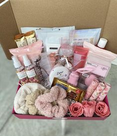 a pink box filled with lots of different items and flowers on top of a table