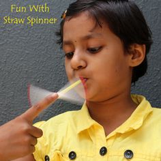 a little boy is blowing out something with his fingers and looking at the camera while wearing a yellow shirt that says, fun with straw spiner