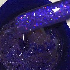 a purple and blue nail polish sitting on top of a black bowl with glitter in it