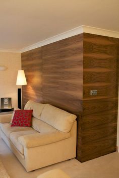 a living room with a white couch and wooden paneling on the wall behind it