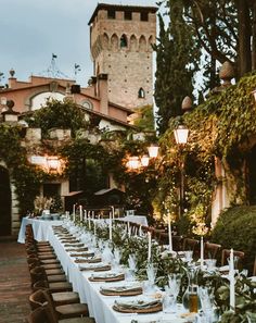 a long table is set with place settings for an outdoor dinner in front of a castle