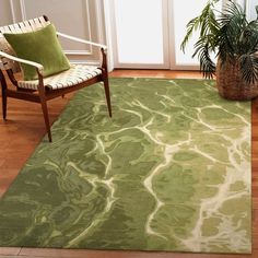 a green rug with white swirls on it in front of a chair and potted plant