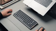 a person using a computer keyboard and mouse on a desk with other office supplies nearby