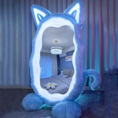 a blue cat shaped mirror sitting on top of a floor next to a bed in a room