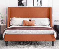 a bed with two pictures on the wall above it and an orange upholstered headboard