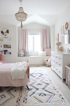 a white bedroom with pink curtains and pillows on the window sill next to a bed