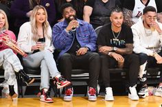 people sitting in the stands at a basketball game, one man is holding a drink