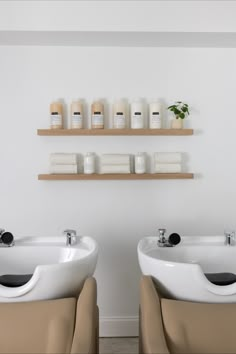 two white sinks sitting next to each other on top of wooden shelves in a bathroom