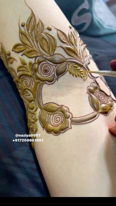 a woman is getting henna done on her arm and leg with scissors in hand