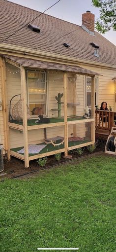 a woman sitting on the back porch of a house with her cat in it's cage