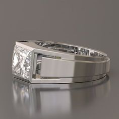 a white gold ring with a princess cut diamond set in the center, on a reflective surface