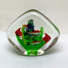 a glass bowl with fish in it sitting on a table top next to a white wall