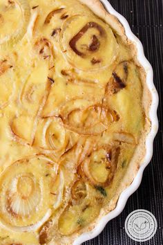 a quiche with onions and cheese in a white dish on a black tablecloth