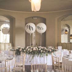 two balloons that say mr and mrs sitting on top of a table with white linens