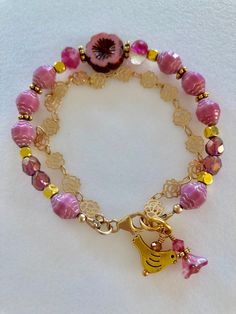 Lovely double strand beaded Premium Czech glass flower bracelet featuring Picasso pink turbine beads, Czech pink sea glass, pink cherub fire polished crystals, and single 15 mm pink Picasso pansy flower. All accented with antique gold plated daisies and shiny cubes. Satin Hamilton rose chain adds the perfect delicate second strand. Premium gold electroplated brass chain in satin finish with intricate rose flower pattern. Bracelet is beaded on professional Soft Flex beading wire with high quality Fun Halloween Earrings, Pink Picasso, Rose Flower Pattern, Polished Crystals, Black Cat Earrings, Pattern Bracelet, Pansy Flower, Pink Sea, Pink Rose Flower