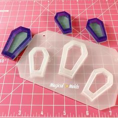 three plastic molds sitting on top of a pink cutting mat next to a ruler