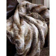 an animal fur blanket on top of a leather chair in a living room next to a fireplace