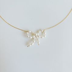 Get ready to add a touch of sweetness to your look with our hand-crafted Pearl Bow Pendant Necklace! This dainty necklace features a fun and flirty bow design set in a 14k gold filled chain. Its ultra-feminine aesthetic is both kitschy and classic, making it the perfect accessory for any occasion. -- freshwater pearls: 4mm flat cable link chain necklace length: 16" and 18" 14k Gold Filled Delicate Bow Necklace For Gifts, Pearl Jewelry With Bow Detail, Bead Bow Necklace, Gold Necklaces With Bow Detail, Necklaces Pearl Bow, Bow Pendant, Pearl Bow, Hoop Charms, Ultra Feminine