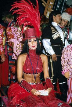 a woman in a red costume sitting on the ground next to other people wearing costumes