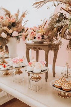 a table topped with cakes and pastries covered in frosting sitting next to flowers