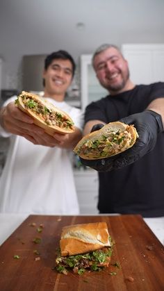 two men are holding sandwiches in their hands