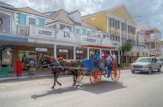 a horse drawn carriage is traveling down the street in front of shops and businesses on a cloudy day