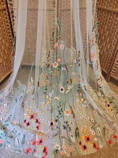 the sheer fabric is decorated with flowers and vines, along with white netting hanging from it's sides