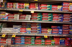 many different types of toothpaste are on the shelves in a store, and one is labeled colgate