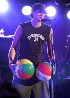 a man holding two large balls in front of a microphone and singing into a mic