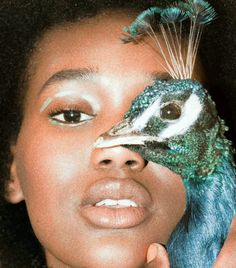 a young woman holding a peacock on her face