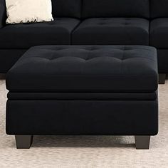 a black couch and ottoman in a living room with carpeted flooring on the side