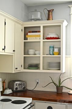 a kitchen with white cabinets and wooden counter tops, an electric stove top oven and microwave