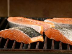 salmon fillets are cooking on an outdoor grill