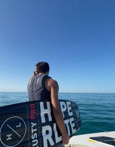 a man holding a surfboard on top of a boat